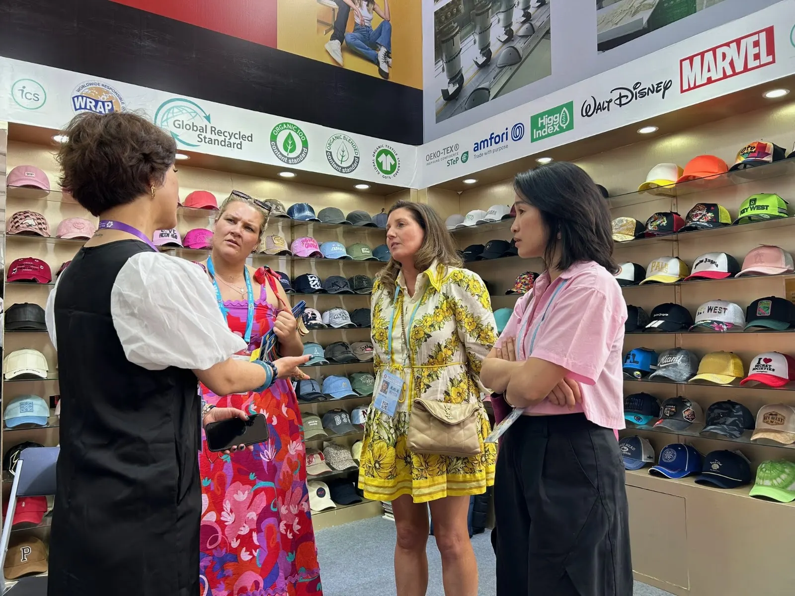 Source Haus sourcing trip participants speaking with a supplier beside shelves of caps at the Canton Fair