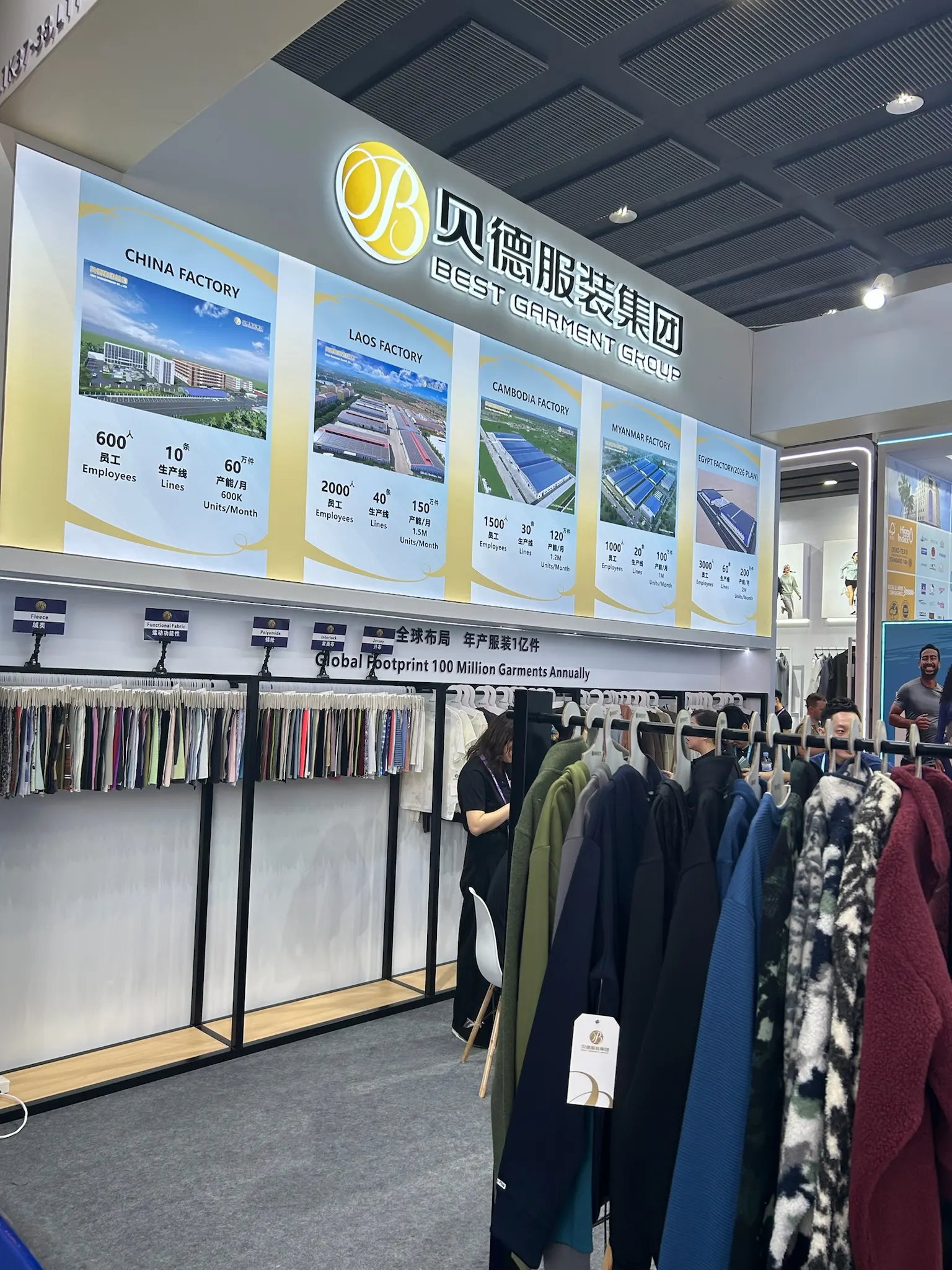 Garment supplier stand at Canton Fair with clothing racks, fabric samples and factory display panels
