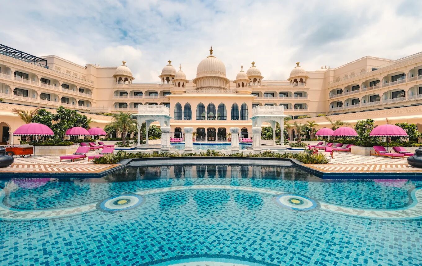Hotel courtyard in Udaipur with a swimming pool, domed architecture and pink parasols