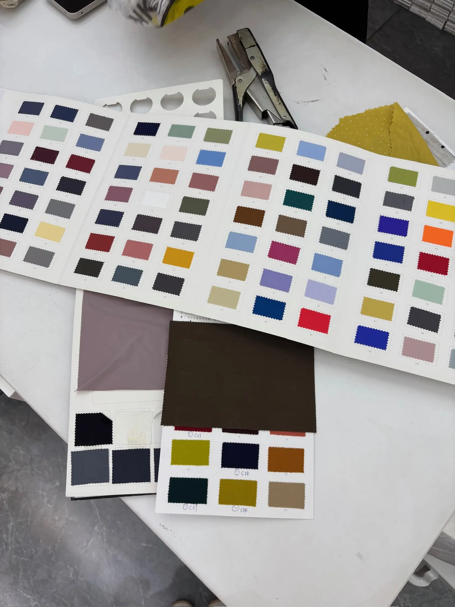 Fabric colour swatch books spread across a supplier's table for material selection