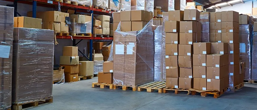 Cardboard cartons stacked on wooden pallets inside a warehouse